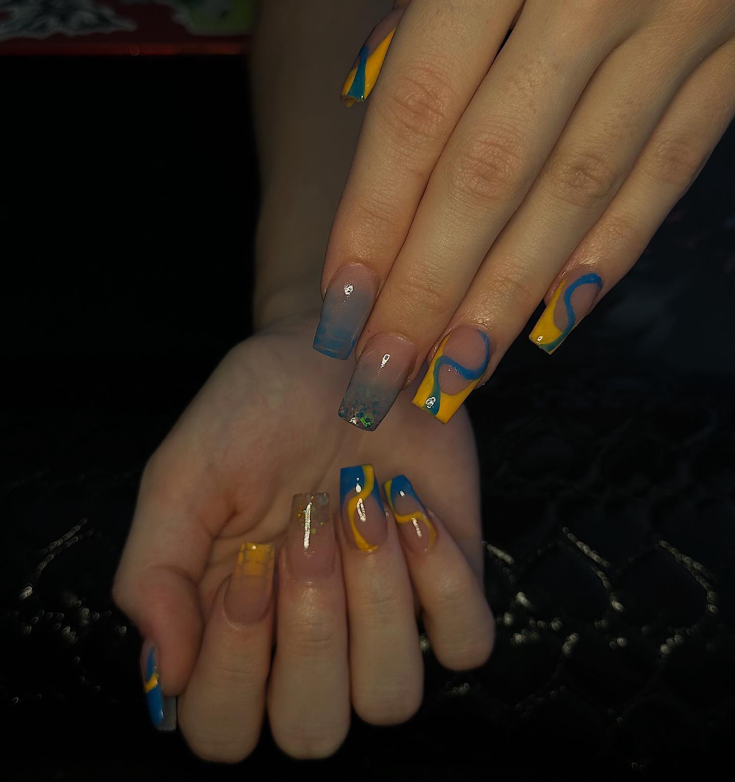 Tourbillons bleus et jaunes et pointes françaises sur de longs ongles carrés effilés en acrylique