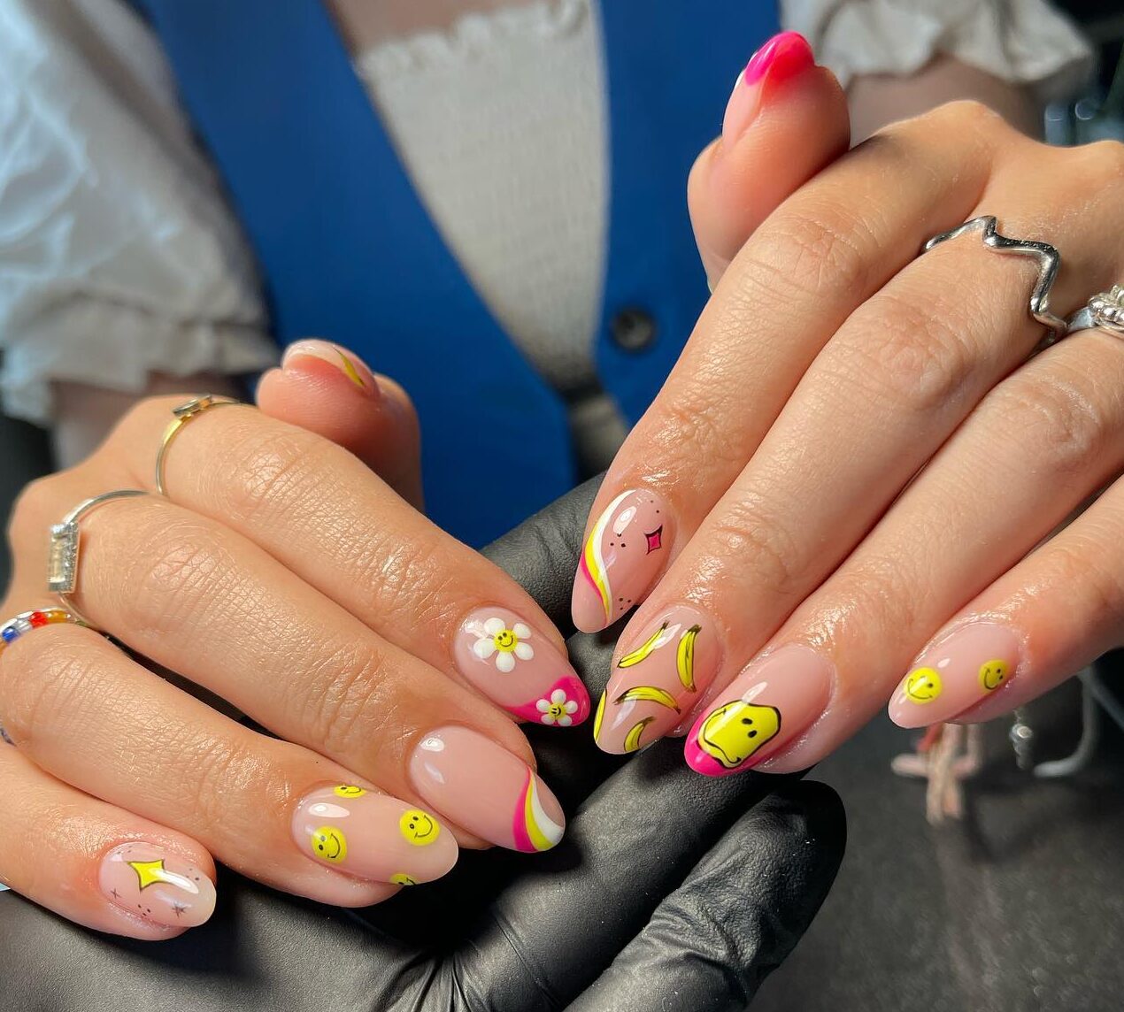 Ongles en acrylique de forme ronde moyenne avec des smileys jaunes, des tourbillons et un nail art floral