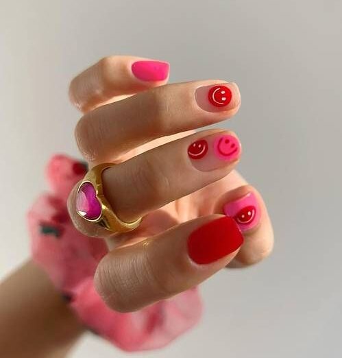 Vernis à ongles rose et rouge avec des smiley roses et rouges, nail art sur ongles courts et carrés