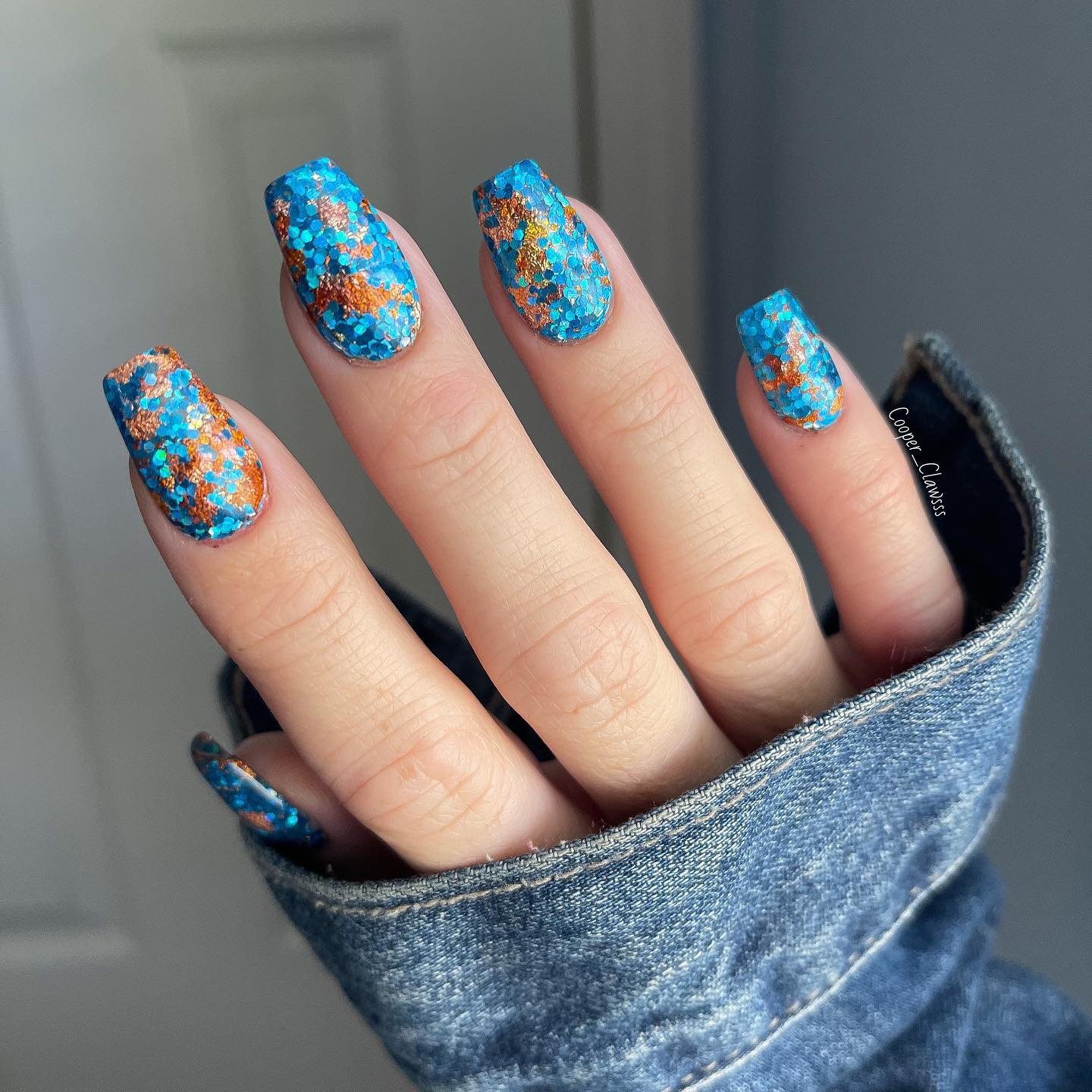 Vernis à ongles à paillettes bleues avec des accents dorés sur les ongles de cercueil moyens