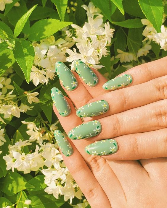 Vernis à ongles vert avec des fleurs sur des ongles en amande