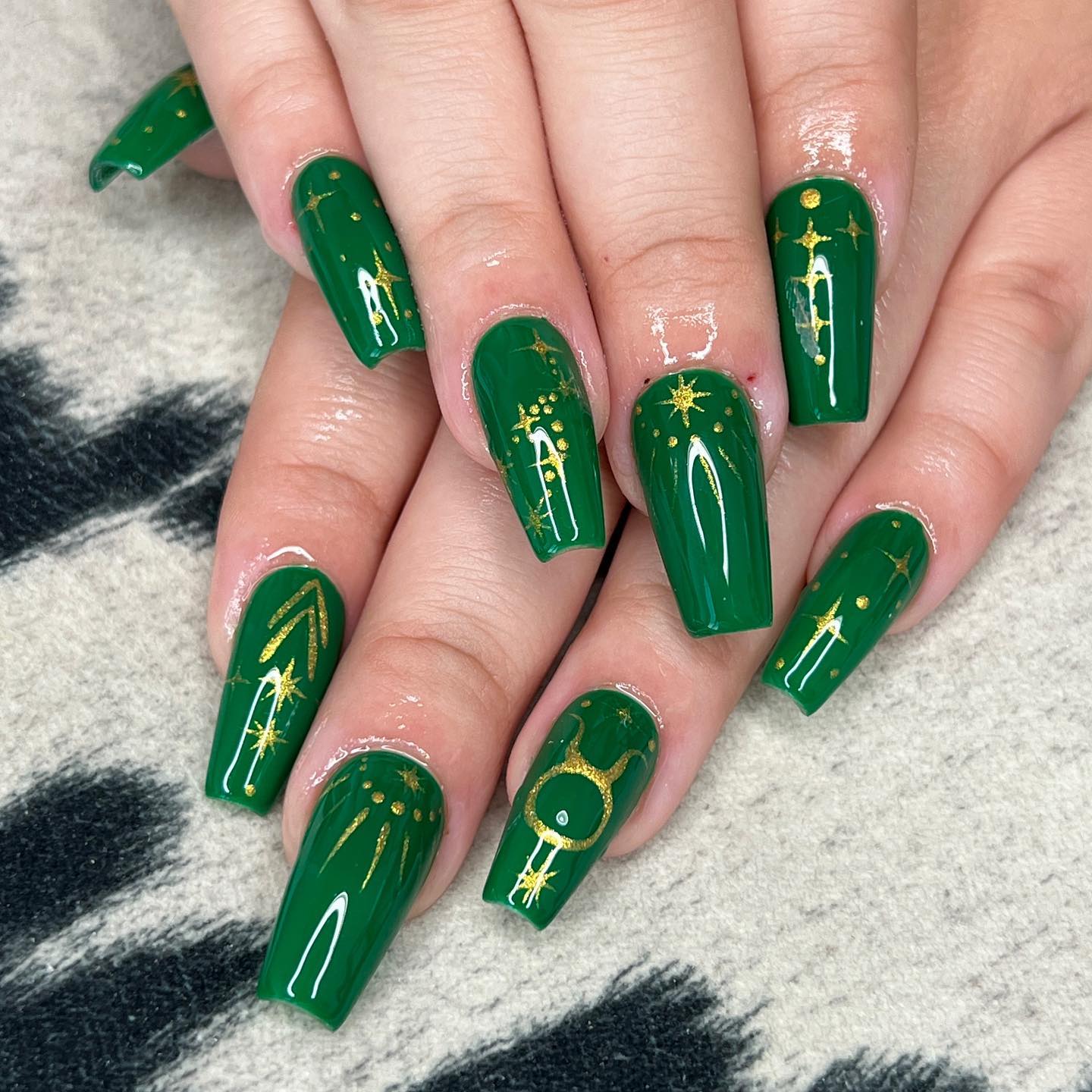 Vernis à ongles vert foncé au fini brillant avec signe Taureau et éléments célestes nail arts sur de longs ongles de cercueil