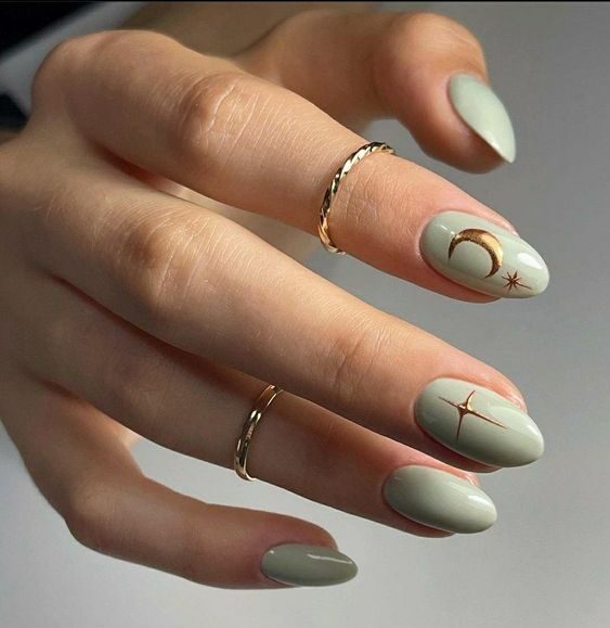 Vernis à ongles vert sauge en finition brillante avec des éléments célestes nail arts sur ongles ronds moyens