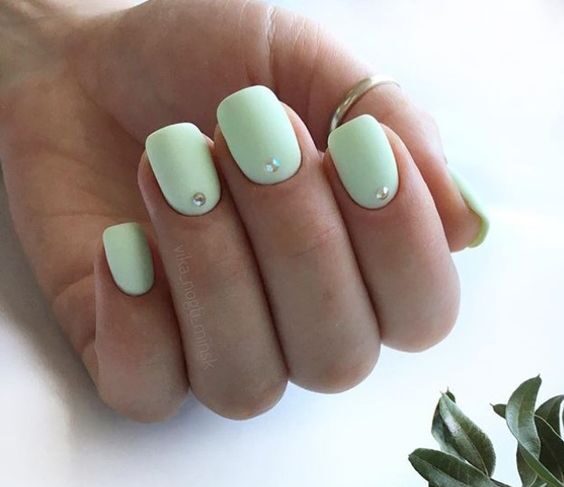 Vernis à ongles vert pâle au fini mat avec pierres sur ongles carrés courts et effilés