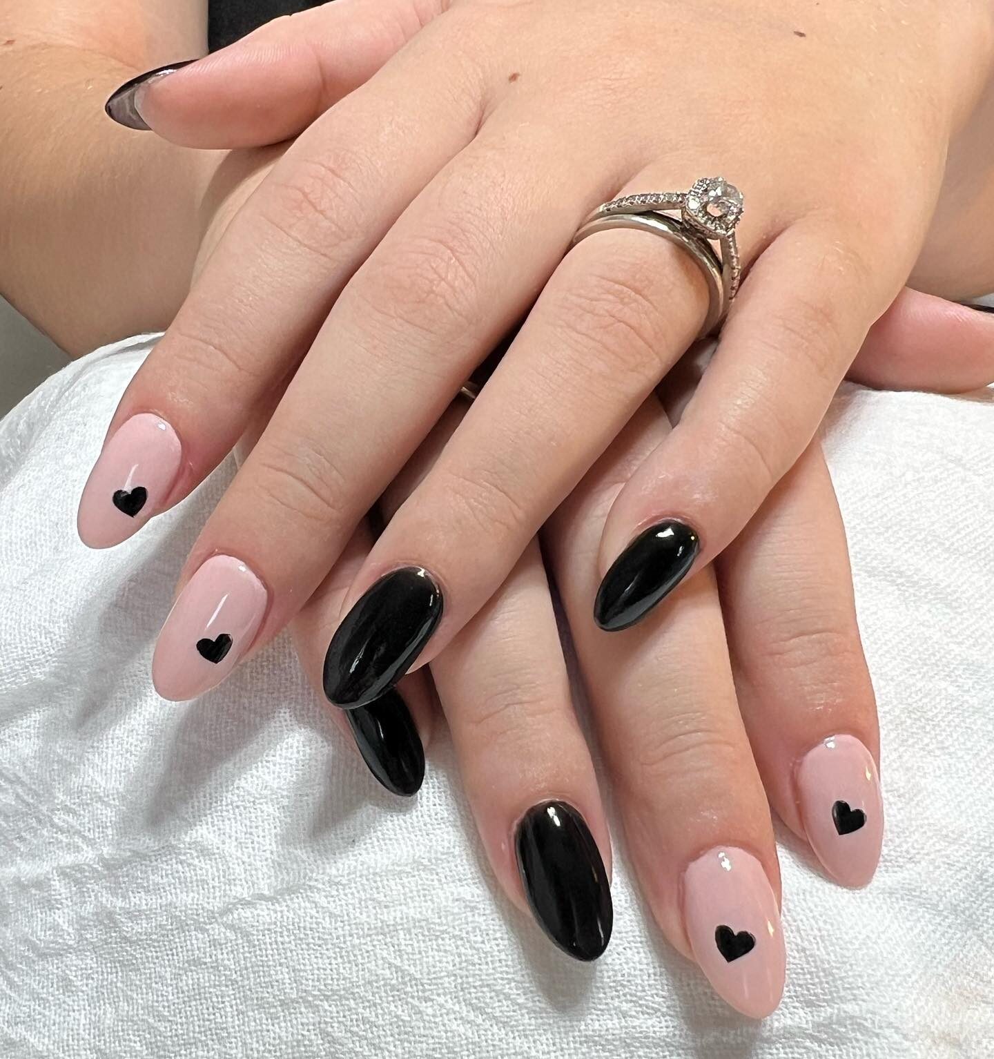 Finition brillante couleurs d’ongles nude et noires avec des cœurs noirs sur les ongles ronds moyens