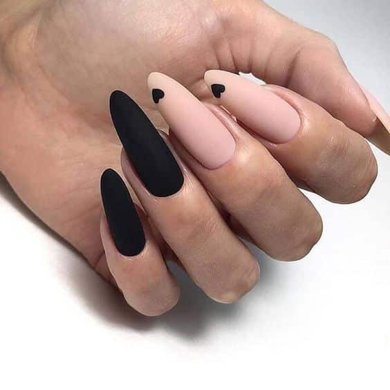 Vernis à ongles nude et noir au fini mat avec des cœurs noirs sur les ongles longs en amande