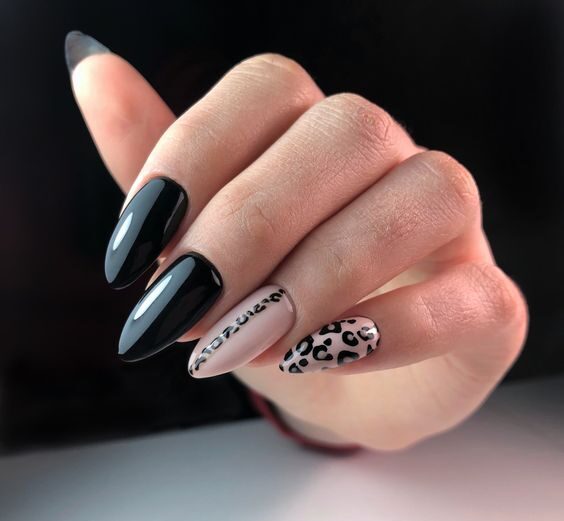 Couleurs d’ongles noires et nude avec nail art imprimé léopard sur de longs ongles en amande