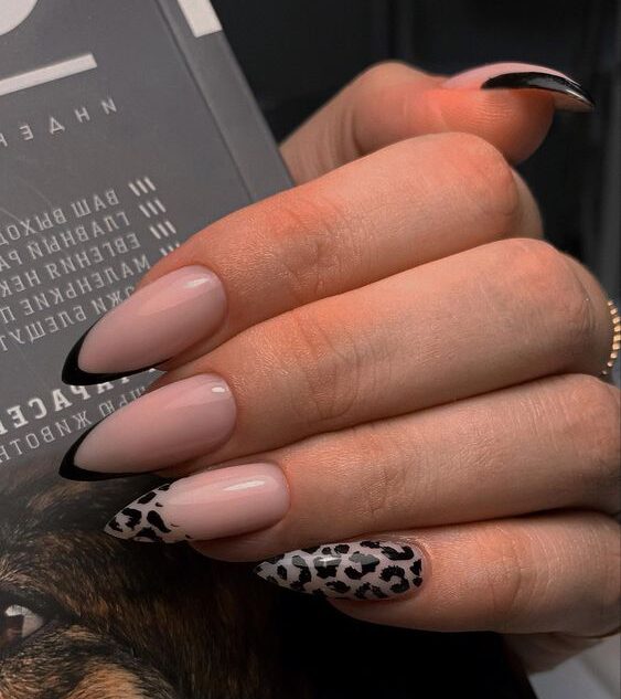 Couleur d’ongle nude avec des pointes françaises noires et un nail art imprimé léopard sur des ongles longs à talons aiguilles