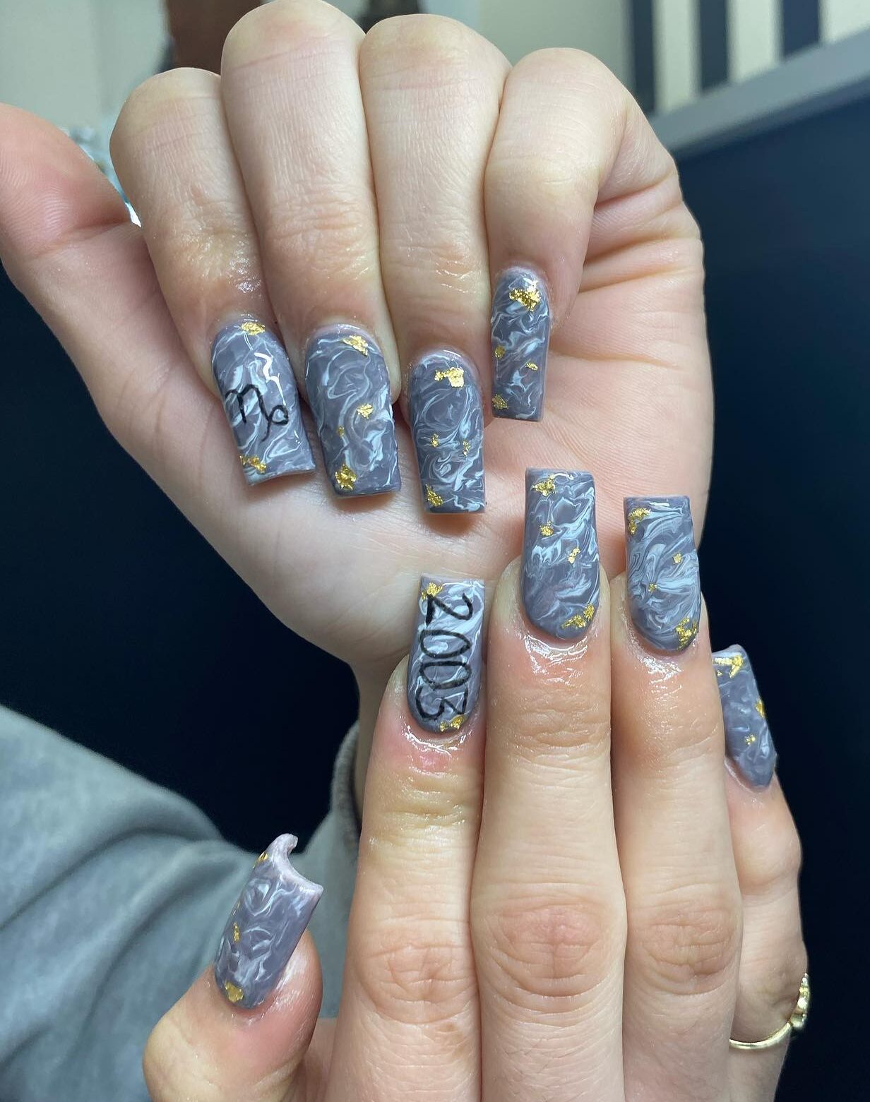 Couleur d’ongle gris mat avec nail art en marbre fumé et feuille d’or sur de longs ongles carrés