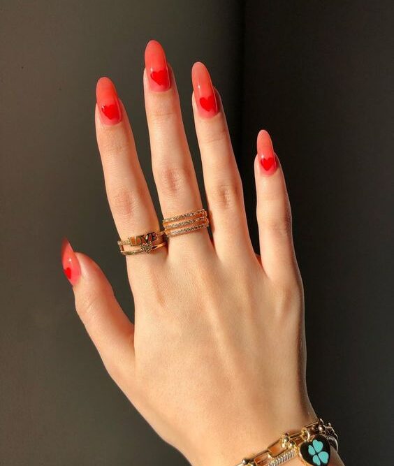 Vernis à ongles rouge pâle avec des cœurs rouges conception d’ongles sur de longs ongles ronds