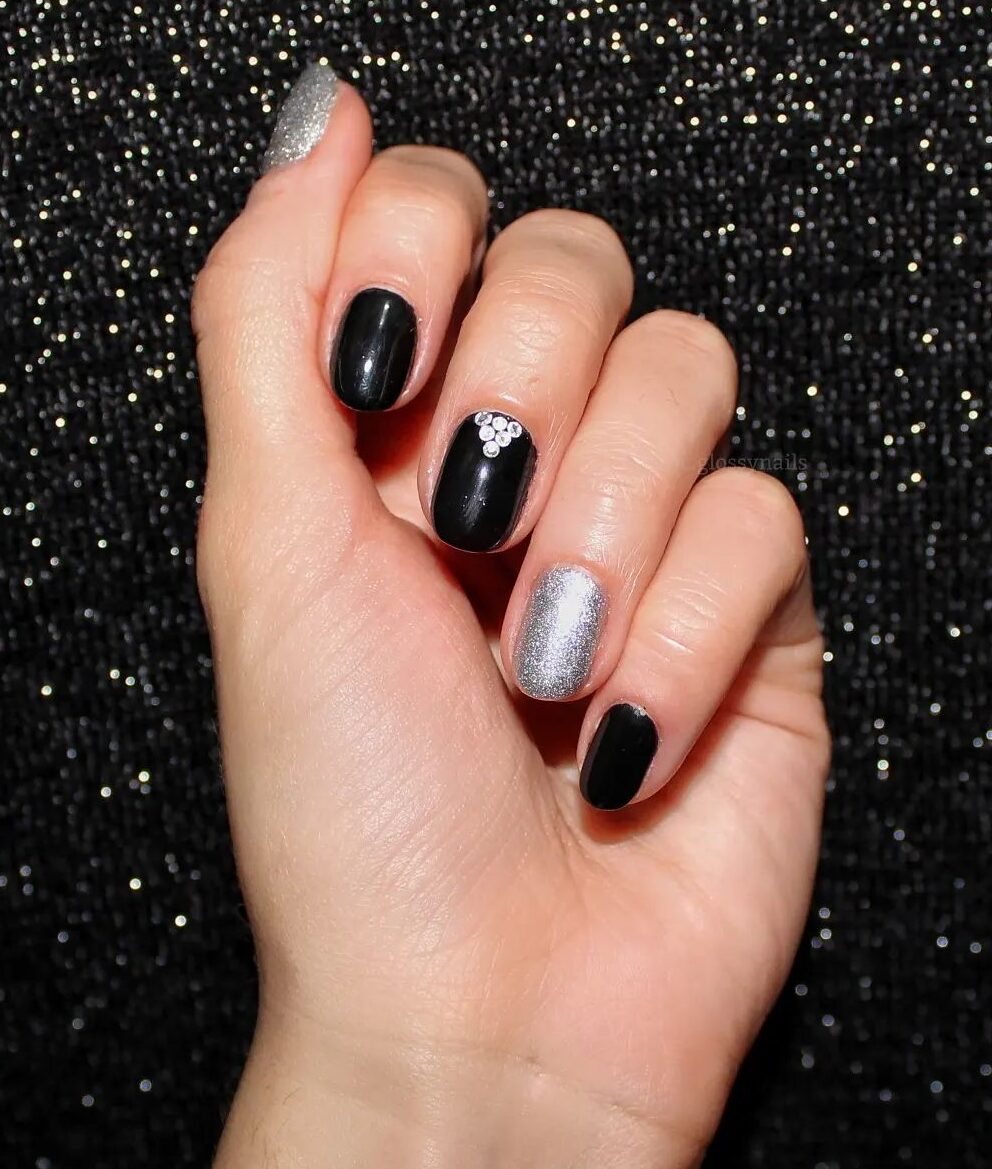 Vernis à ongles de couleur noire et argentée avec des pierres sur les ongles ronds courts