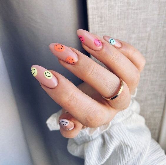 Ongles en amande nude avec des motifs d’ongles multicolores smiley