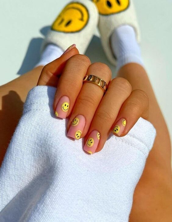 Vernis à ongles de couleur rose avec smiley jaune nail art sur ongles carrés courts