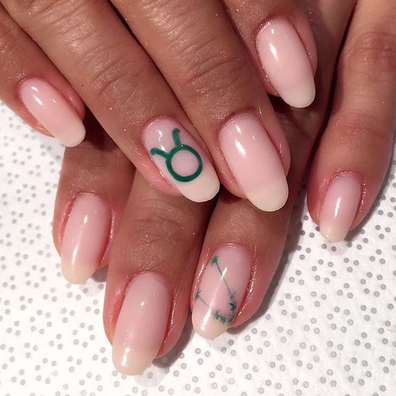 Couleur d’ongle blanc pâle avec un nail art minimaliste du signe Taureau sur des ongles ronds moyens