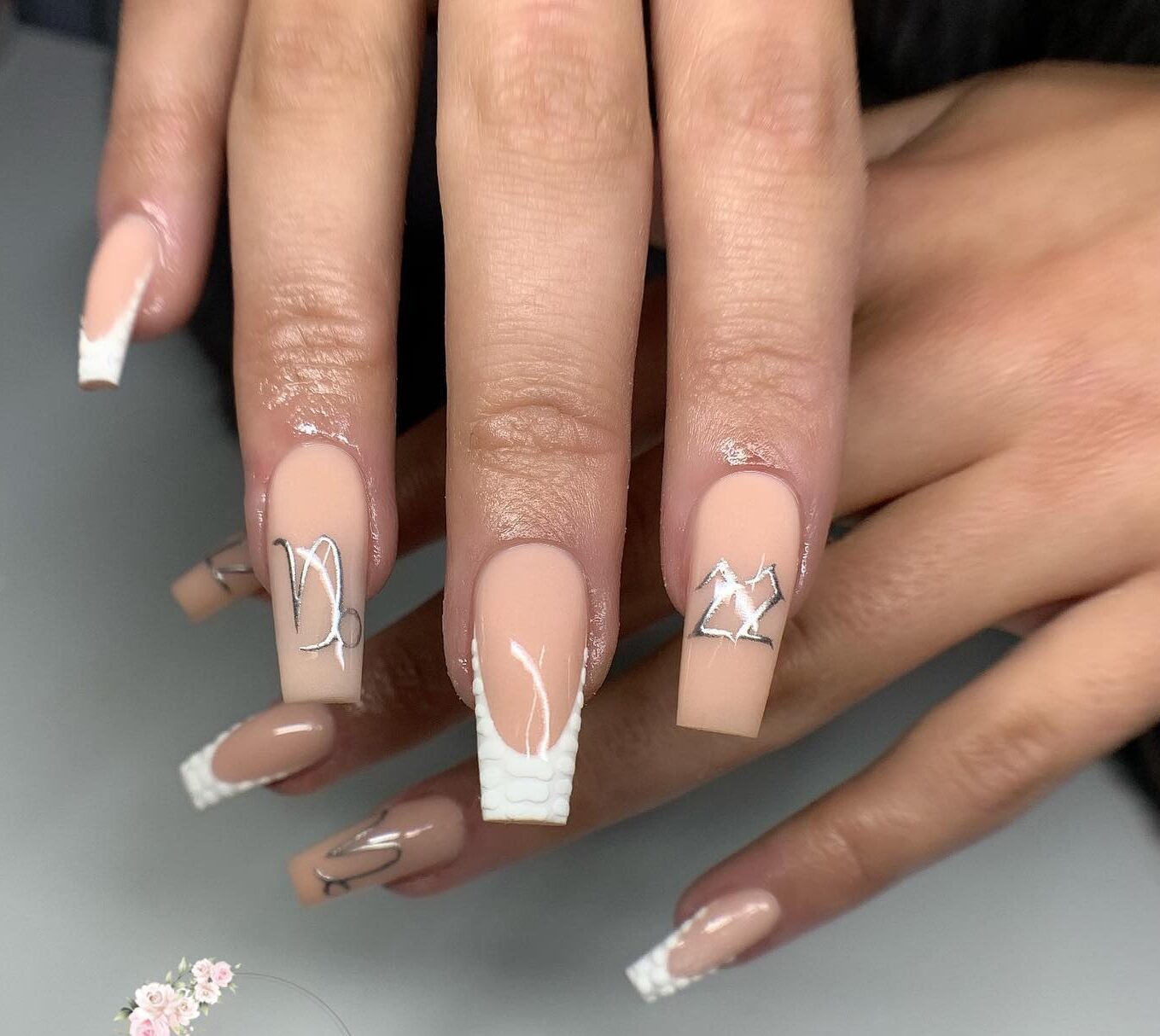 Vernis à ongles nude avec pointes blanches Françaises et nail arts symbole Capricorne sur ongles carrés longs et effilés