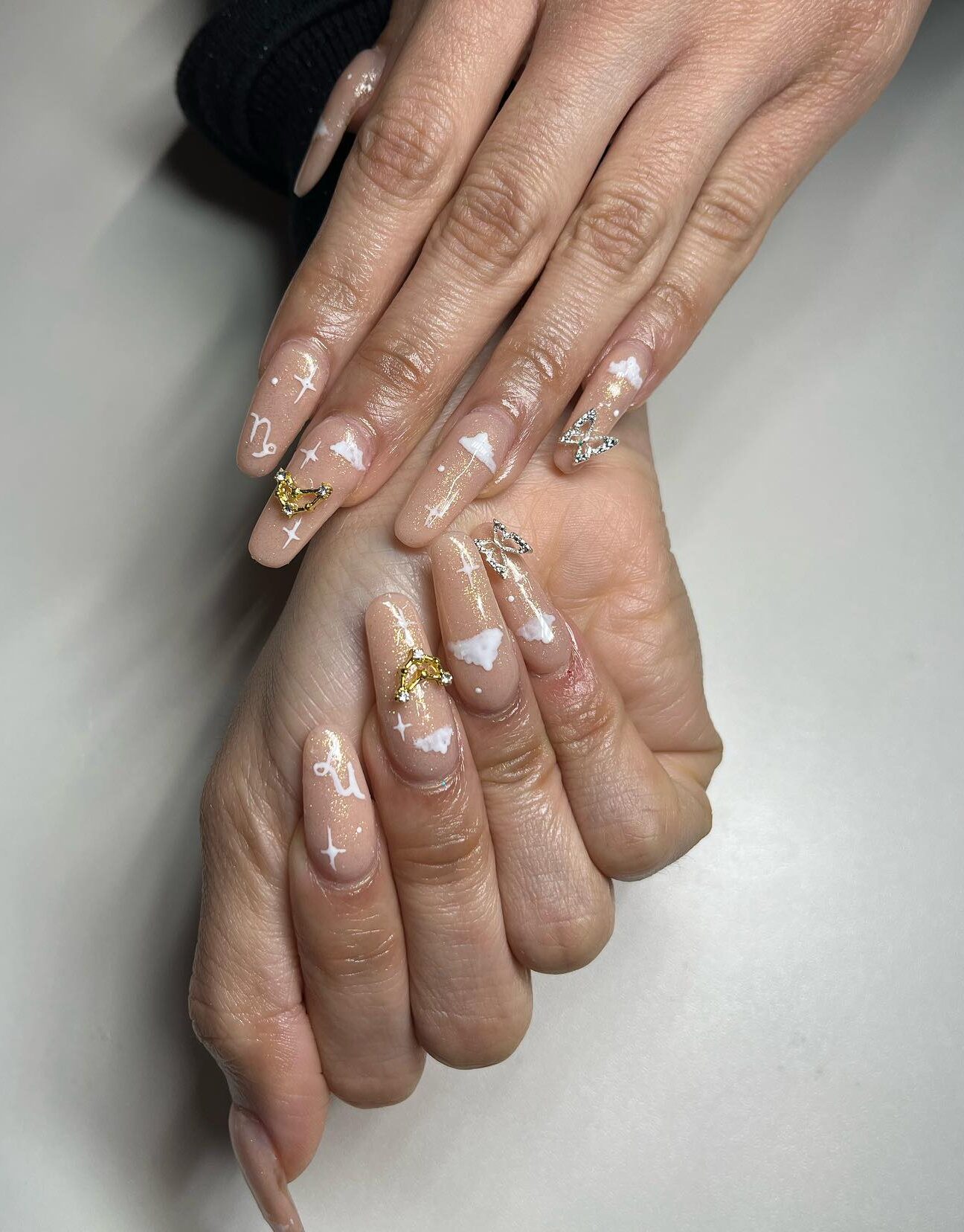 Vernis à ongles de couleur nude avec 3D Capricorne bling et éléments célestes sur de longs ongles en acrylique de forme ovale