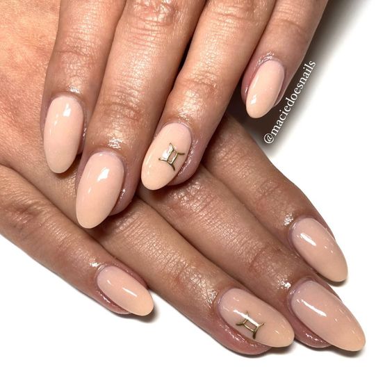 Vernis à ongles de couleur crème avec signe Gemini doré nail art sur ongles ronds moyens