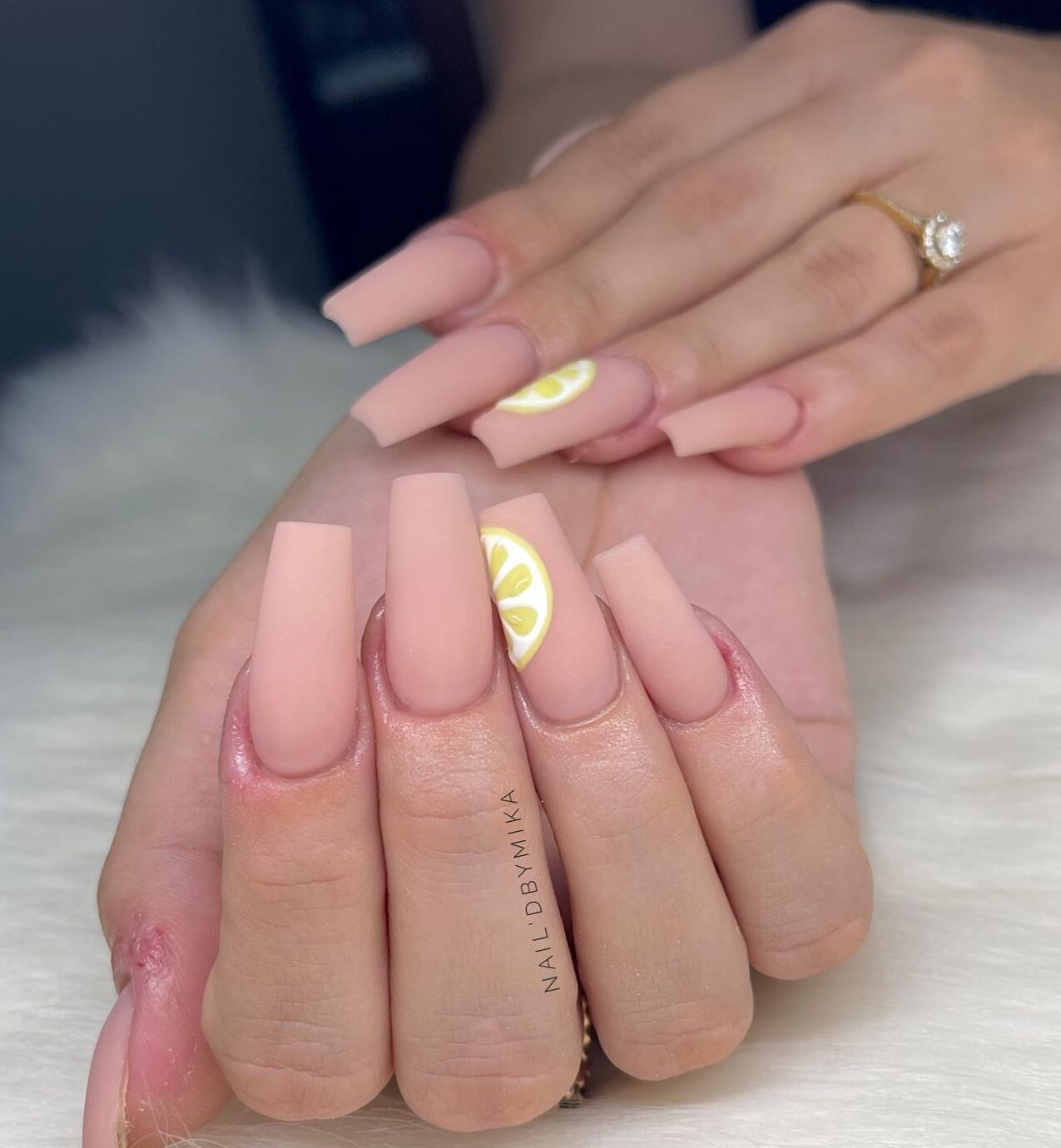 Vernis à ongles de couleur neutre au fini mat avec des nail arts citron sur les ongles carrés longs et effilés