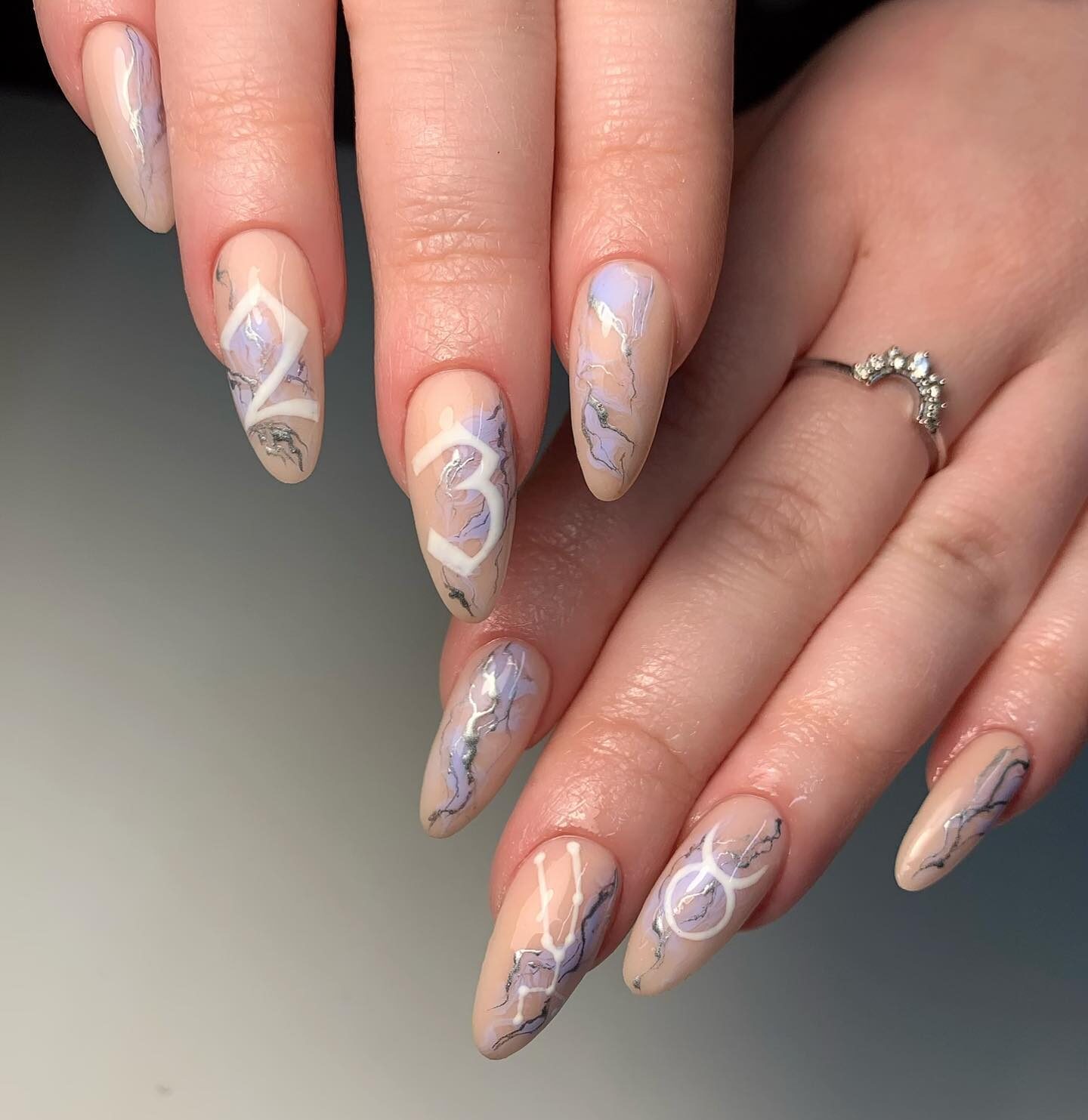 Vernis à ongles nude avec nail art en marbre lavande et signe Taureau sur de longs ongles ronds