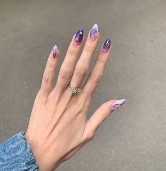 Conception d’ongles ombré violet et marbre avec des éléments célestes nail arts sur de longs ongles à talons aiguilles