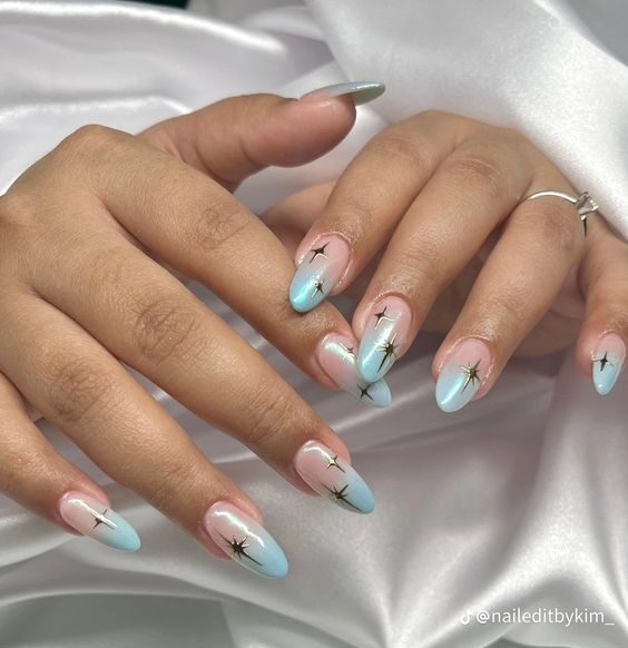 Effet ombré bleu clair avec des motifs d’ongles célestes sur de longs ongles ronds