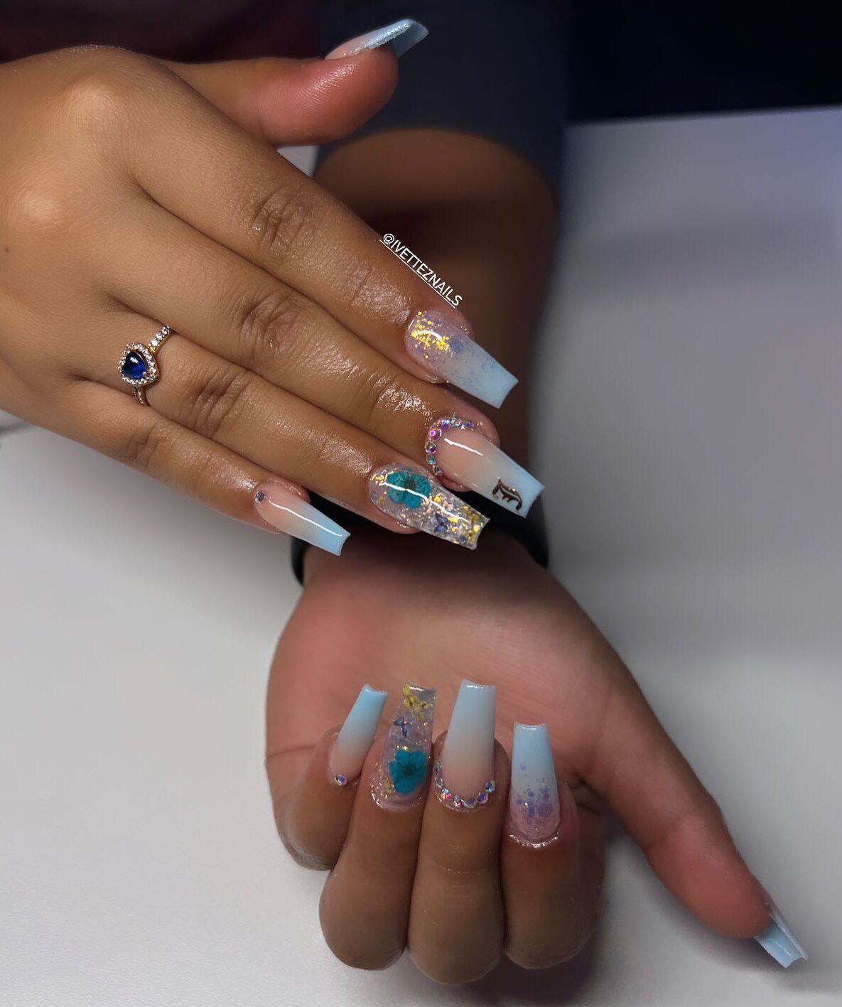 Nail art ombré bleu clair au fini brillant avec des paillettes et des pierres sur de longs ongles carrés effilés en acrylique