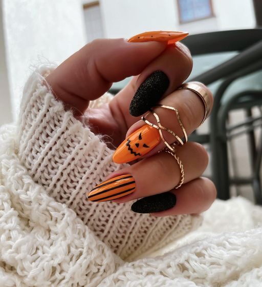 Couleurs d’ongles noires et oranges avec nail art d’Halloween sur ongles en amande moyens