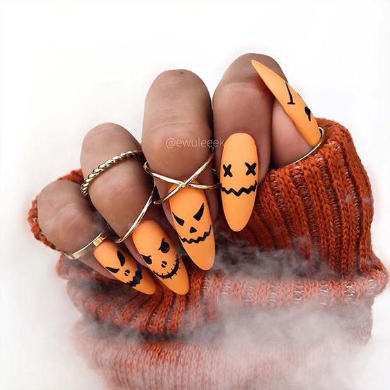 Vernis à ongles orange mat avec des visages effrayants nail arts sur ongles longs en amande