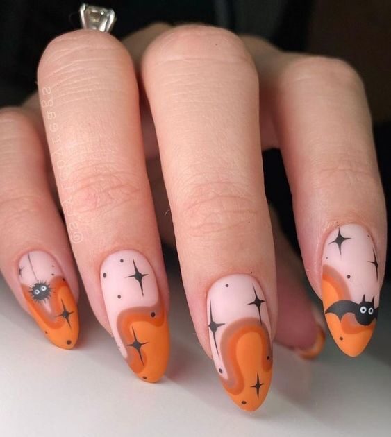 Pointes françaises tourbillonnantes d’orange avec des motifs d’ongles d’Halloween sur de longs ongles en amande