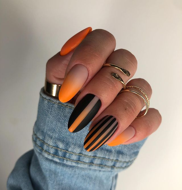 Combinaison orange et noire de couleurs d’ongles sur les ongles en amande