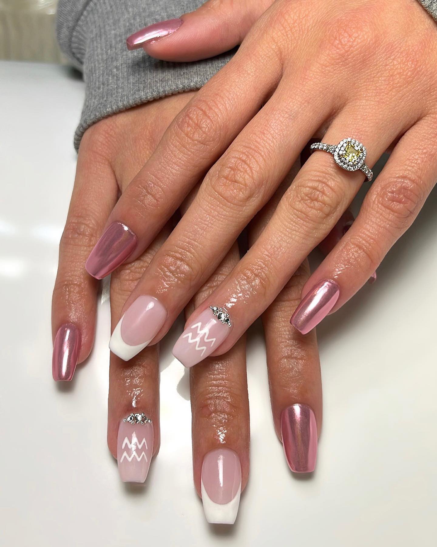 Vernis à ongles rose chrome, pointes françaises blanches et motifs d’ongles de signe Verseau sur les ongles de cercueil moyens