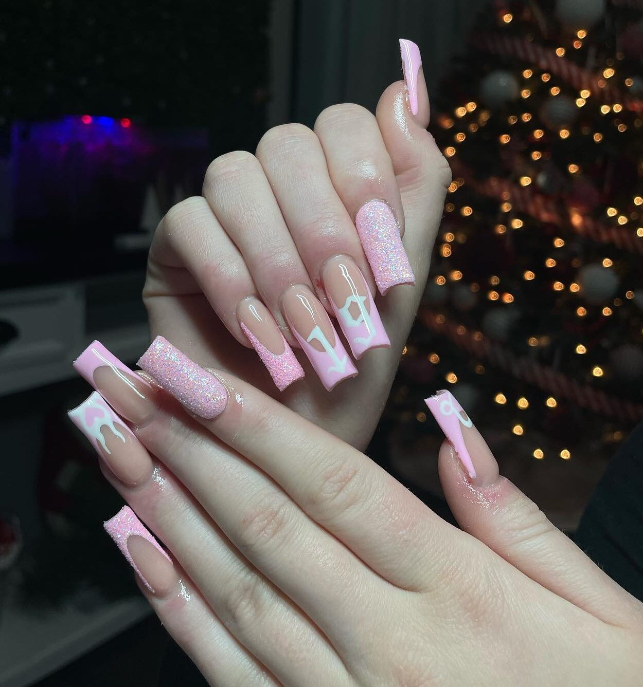 Longs ongles en acrylique de forme carrée avec des pointes françaises rose clair élégantes et un nail art symbole Capricorne