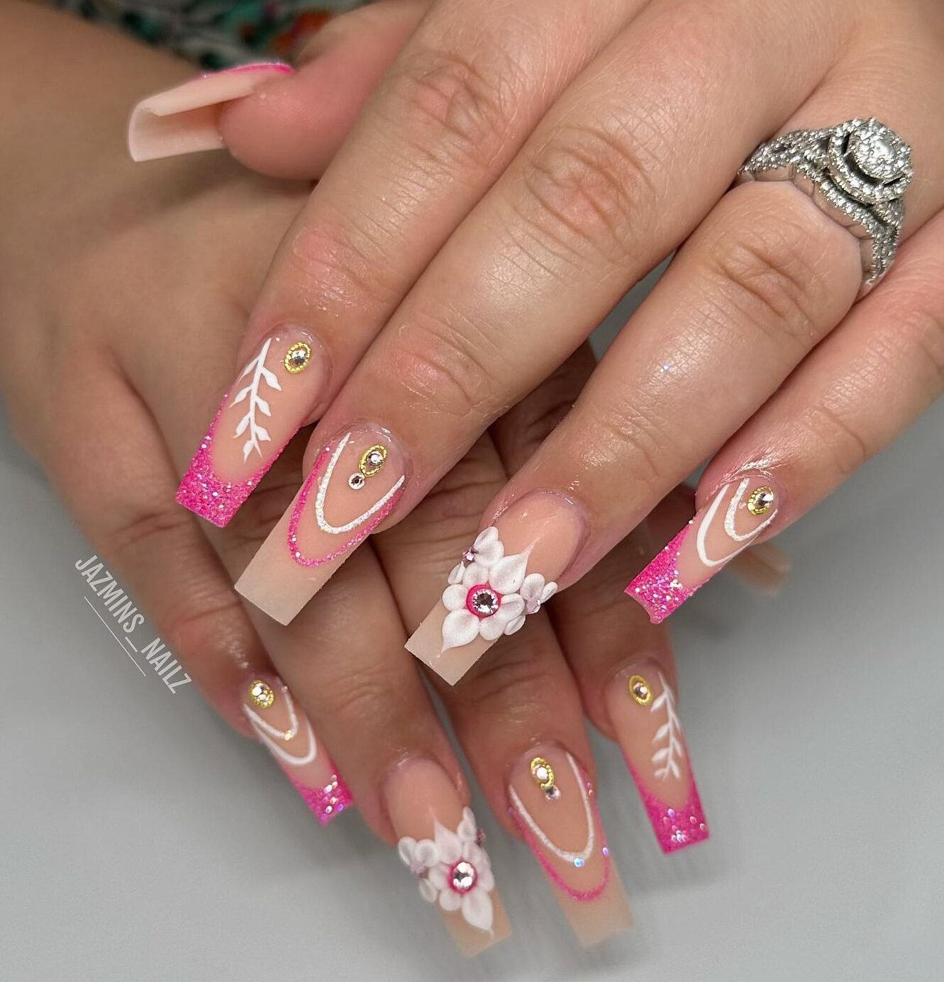 Ongles longs et effilés en acrylique de forme carrée avec des paillettes roses, des pointes françaises et des motifs d’ongles bling 3D