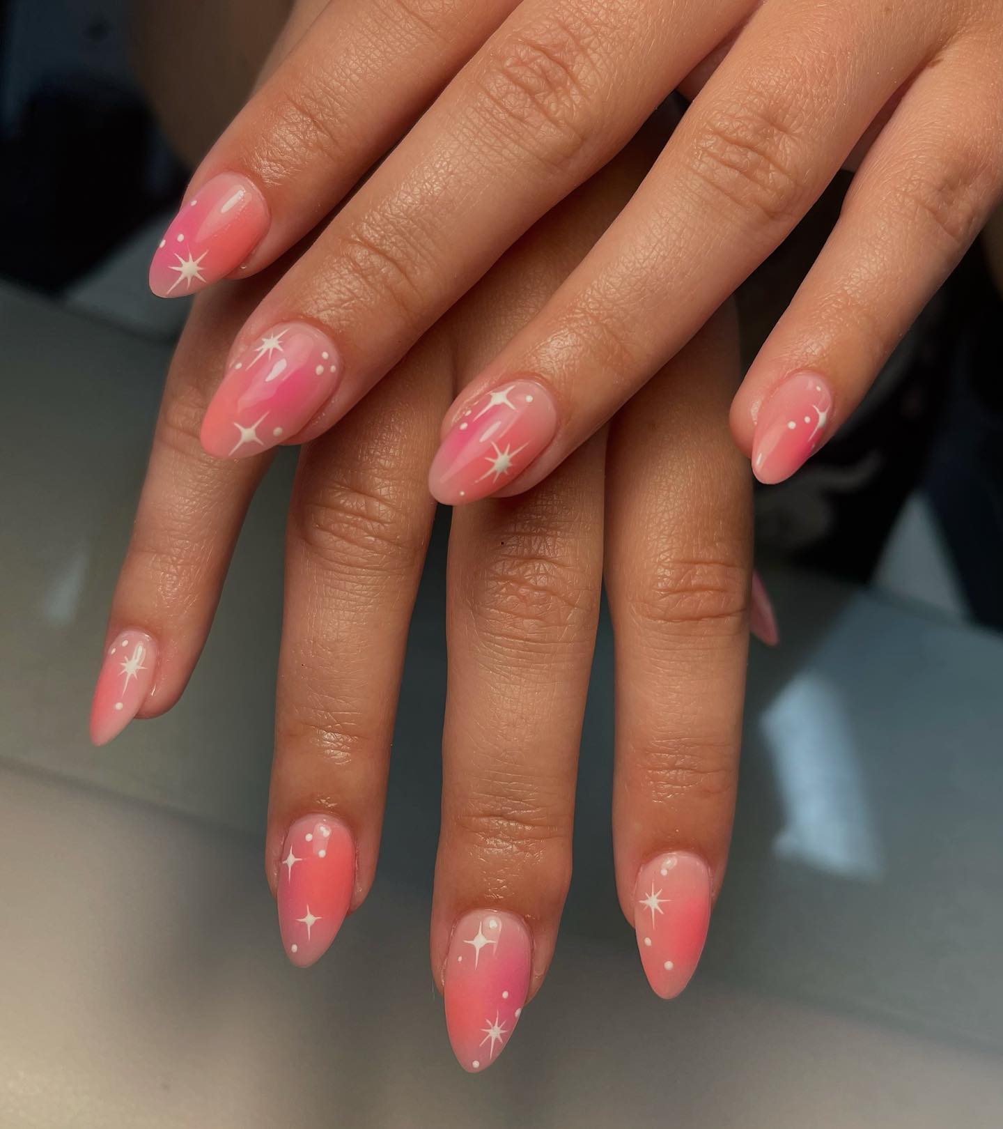 Effet ombré rose et pêche avec des motifs d’ongles d’éléments célestes sur des ongles en amande moyenne