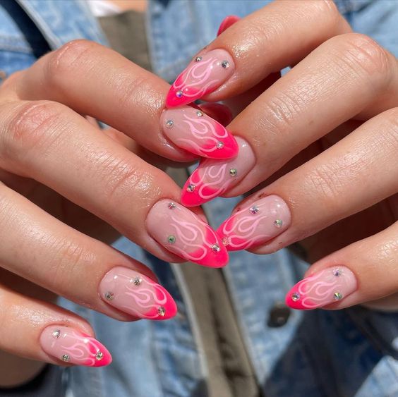 Vernis à ongles de couleur beige avec des pointes françaises rose fluo, des flammes rose clair et des strass sur les ongles longs en amande