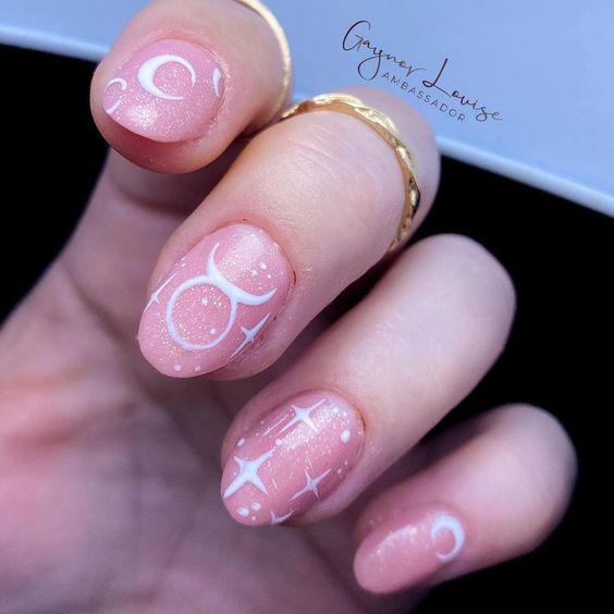 Vernis à ongles à paillettes rose pâle avec signe Taureau et éléments célestes nail arts sur ongles ronds moyens