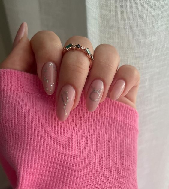 Vernis à ongles rose pâle avec signe Taureau et ongles constellations sur ongles longs et ronds