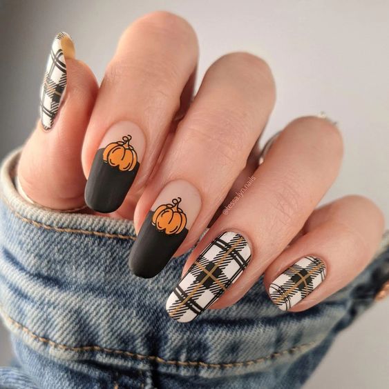 Longs ongles ronds en acrylique avec vernis à ongles noir mat, citrouilles et motifs d’ongles à carreaux