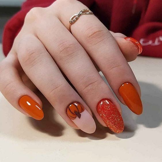 Couleur d’ongles orange brûlé avec paillettes et art d’ongle citrouille sur ongles ronds moyens