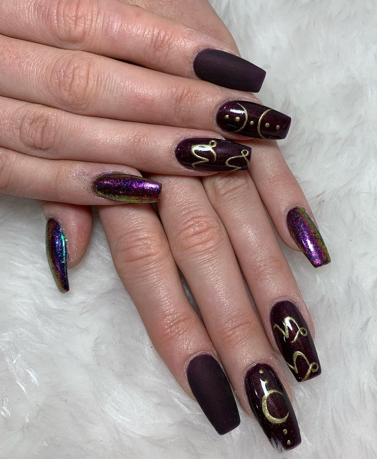 Vernis à ongles violet mat, brillant et métallisé avec des symboles du Capricorne sur de longs ongles de cercueil