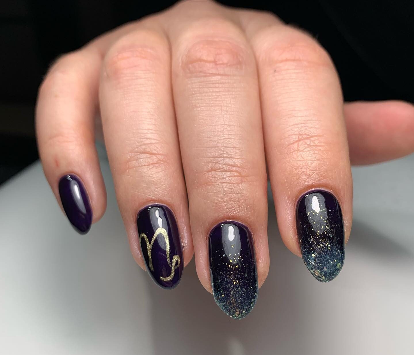 Vernis à ongles violet foncé avec paillettes et symbole Capricorne nail art sur ongles ronds moyens