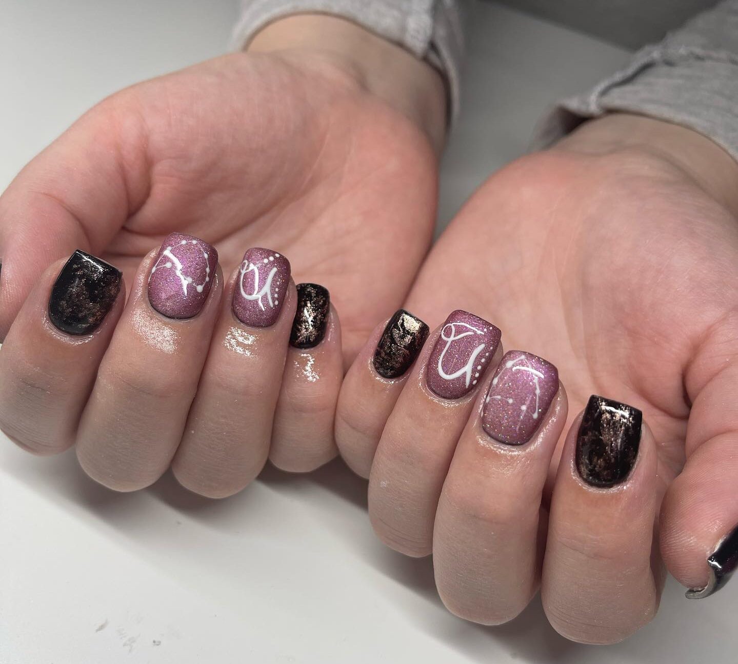 Couleurs d’ongles chrome, violet et noir avec symbole du Capricorne et motifs d’ongles constellation sur des ongles carrés courts