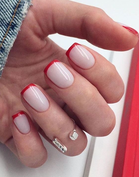 Couleur d’ongle blanc pâle avec de fines pointes françaises rouges sur des ongles carrés courts