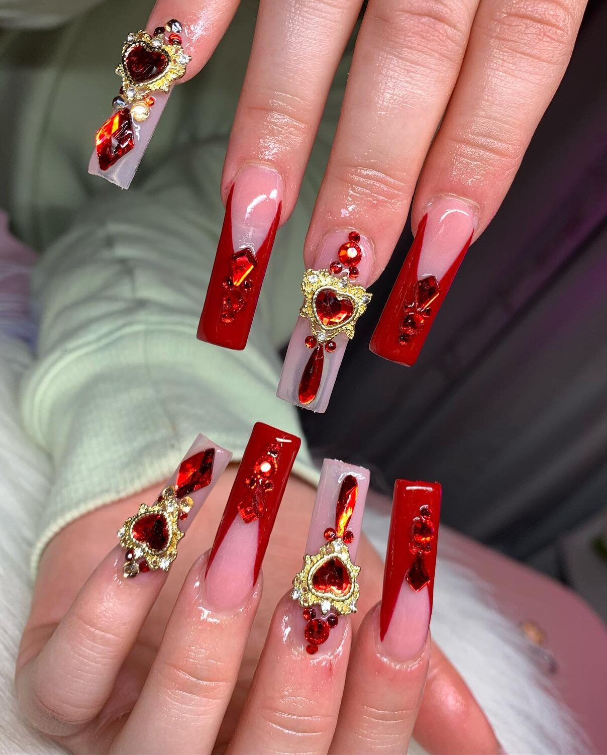 De longs ongles en acrylique transparent avec des pointes françaises rouge vif, des strass et du bling 3D