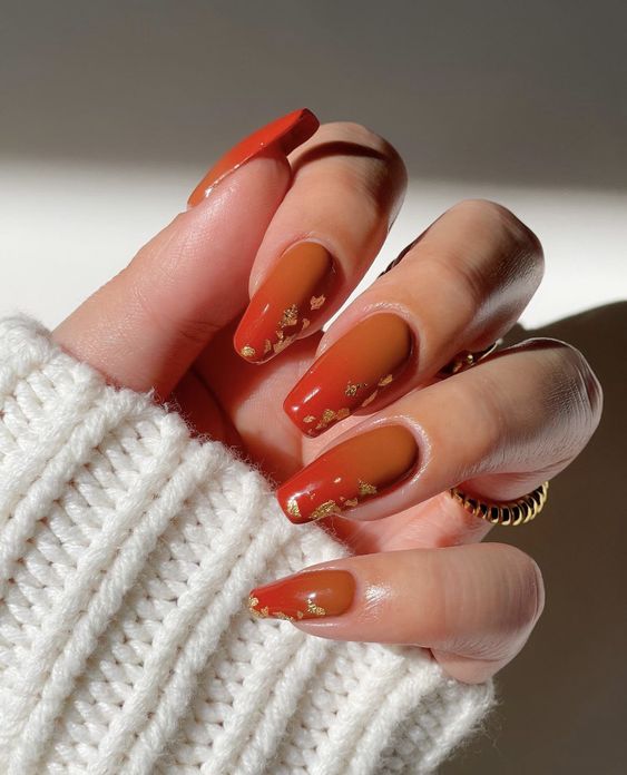 Conception d’ongles ombrés orange brûlé avec des accents de feuille d’or sur de longs ongles carrés effilés