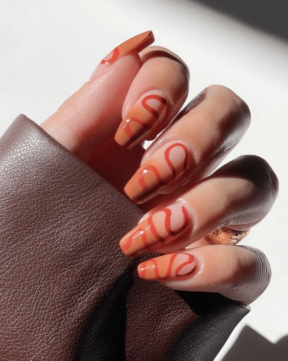 Conception d’ongles ombrés orange brûlé avec des motifs tourbillonnants sur des ongles carrés effilés moyens