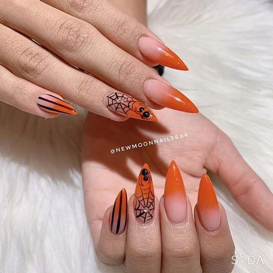 Finition brillante effet ombré orange avec des nail arts inspirés d’Halloween sur de longs ongles à talons aiguilles