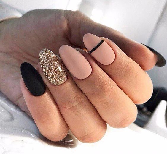 Vernis à ongles nude et noir au fini mat avec des paillettes dorées sur les ongles ronds moyens