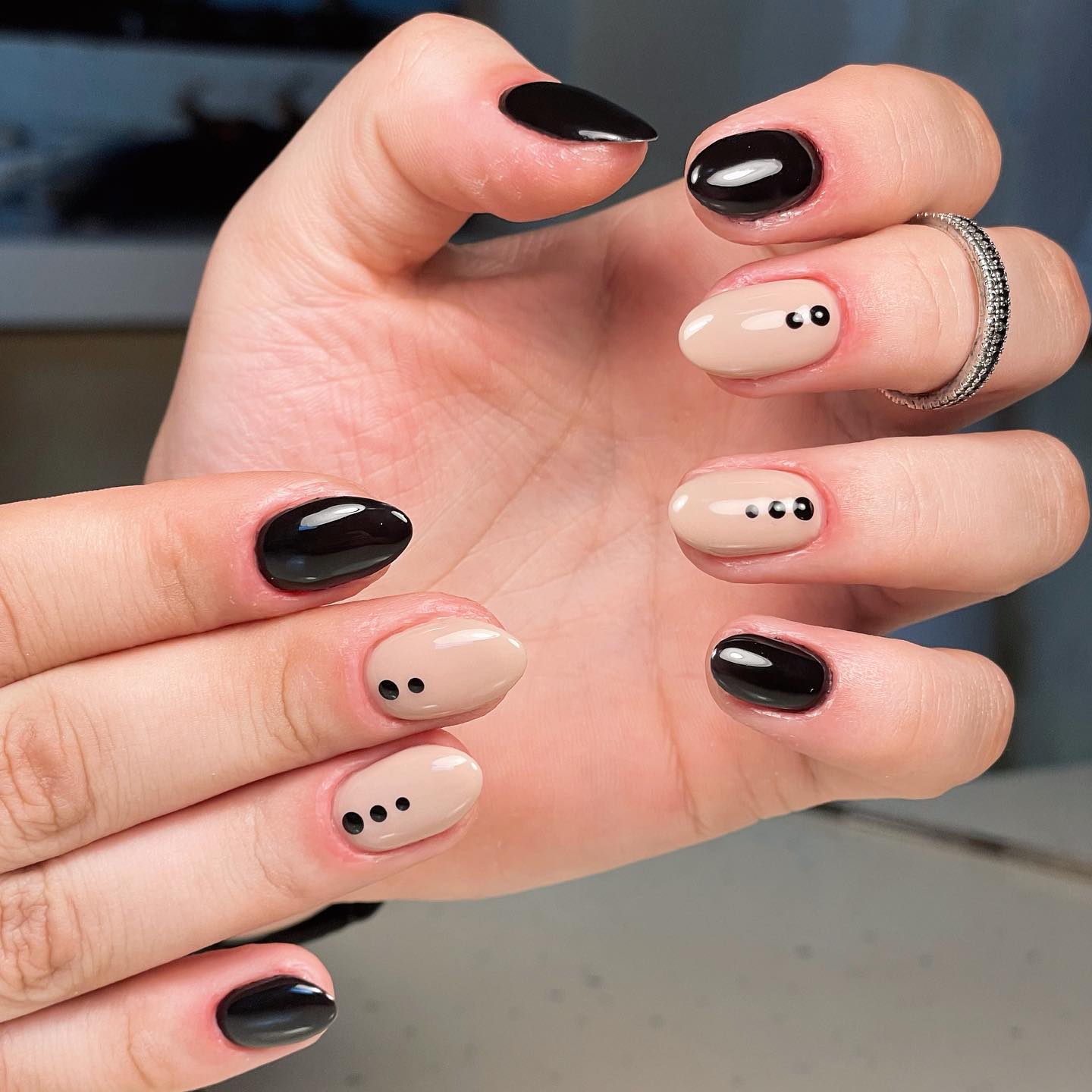 Couleurs d’ongles noires et nude avec des pois noirs conception d’ongles sur des ongles ronds courts