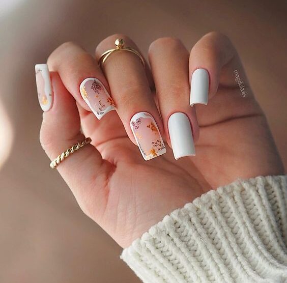 Vernis à ongles de couleur blanche au fini mat avec des motifs de feuilles et de fleurs sur des ongles carrés effilés moyens